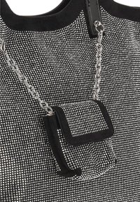 Zwarte handtas met strassversieringen, voorzien van een klein zakje en een zilverkleurige ketting als accent. Gladde textuur met een gestructureerd ontwerp.