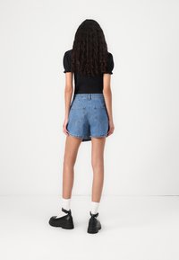 Lys blå denimshorts med avslappet passform, som har baklommer og oppbrettede ben, kombinert med svarte ankelstøvler og hvite sokker.