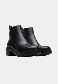 Botas de cuero negro hasta el tobillo con punta redonda, cierre lateral con cremallera y un tacón grueso. Suela texturizada para agarre y estabilidad.