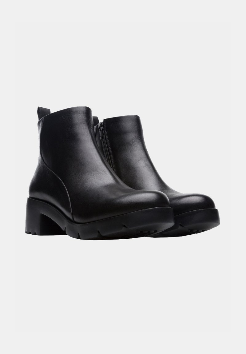 Botas de cuero negro hasta el tobillo con punta redonda, cierre lateral con cremallera y un tacón grueso. Suela texturizada para agarre y estabilidad.