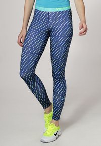 Leggings sportivi blu navy con un motivo diagonale verde neon, realizzati in materiale elasticizzato. Presentano una vita piatta e contrasti accentuati.