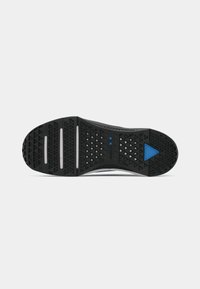 Black shoe sole with triangular tread patterns, three white horizontal traction lines, and a blue triangular detail near the toe area.
