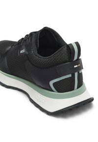 Scarpa da ginnastica nera con materiali in mesh e sintetici. Presenta un design elegante, accenti verde menta e bianco, e superfici testurizzate.