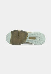 Suola di sneaker con una sezione in gomma marrone texturizzata, un'area in gomma bianca e scanalature per la trazione. Logo circolare impresso sul lato.