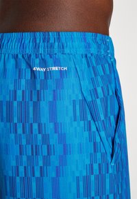 Blue shorts with a geometric pattern in varying shades of blue. Features a drawstring waist and side pockets. Text: "4WAY STRETCH."