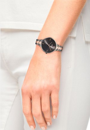 Schwarze Armbanduhr mit rundem Ziffernblatt, metallischen Akzenten und einem gemischten Materialband, das goldene und silberne Glieder aufweist. Einfaches, elegantes Design.
