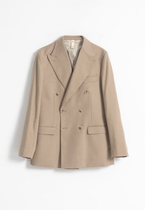 Blazer beige de doble abotonadura confeccionado en tela texturizada, con solapas de pico, cuatro botones y dos bolsillos delanteros.