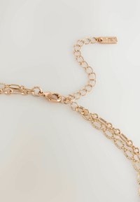 Halskette aus roségoldfarbenem Metall mit ovalen Gliedern, mit einer strukturierten Oberfläche und einem sicheren Karabinerverschluss. Enthält eine verstellbare Verlängerungskette.