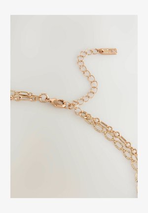 Kedja av roséguld med ovala länkar, med en texturerad yta och en säker karbinhake. Inkluderar en justerbar förlängningskedja.