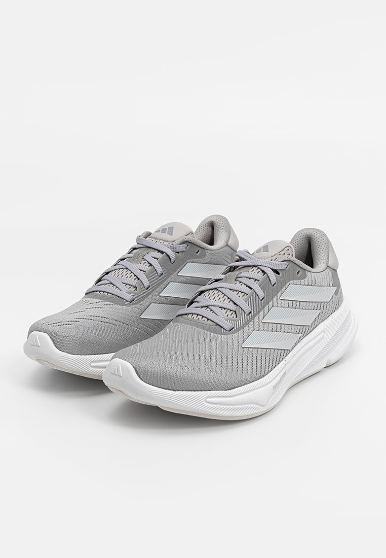 Ein Paar graue Adidas-Laufschuhe mit drei weißen Streifen an den Seiten, weißen gepolsterten Sohlen und grauen Schnürsenkeln auf einem weißen Hintergrund.