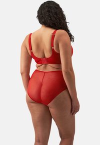 Conjunto de lencería roja que incluye un sujetador liso y texturizado con tirantes ajustables y cierre de gancho, acompañado de unas bragas altas transparentes.