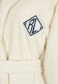 Accappatoio color crema realizzato in morbido spugna, con un logo ricamato di colore blu navy a forma di diamante con "RL." Include una cintura da legare in vita.