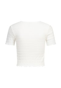 Biały krótki top z krótkim rękawem, teksturowany, z delikatnie falującym dołem i lekko pomarszczonym wzorem na tkaninie.