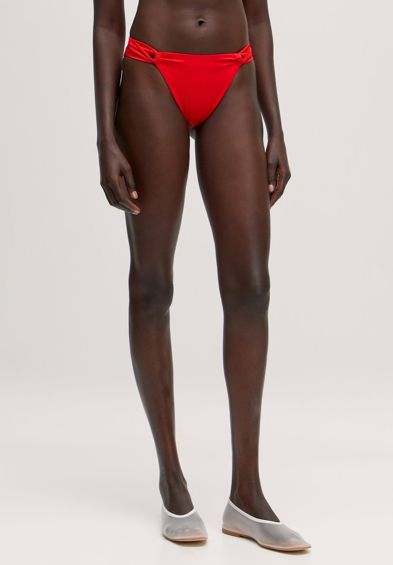 Rote Bikiniunterteile mit einem hochgeschnittenen Design, ausgestattet mit Drehdetails an der Vorderseite. Der Stoff ist glatt und dehnbar für besonderen Komfort.