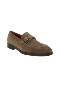 Mocassin en suede brun avec un talon plat, présentant une bande décorative et une boucle, un bout rond et des coutures contrastantes le long de la tige.