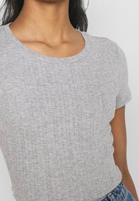 Camiseta de punto acanalado de color gris claro con mangas cortas y escote redondo, con un patrón texturizado en toda la tela.