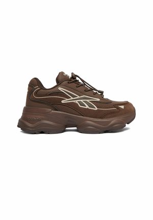 Zapatilla marrón de Reebok con suela gruesa, logo beige en el lateral, parte superior de malla y ante, y cordones elásticos para un fácil ajuste.