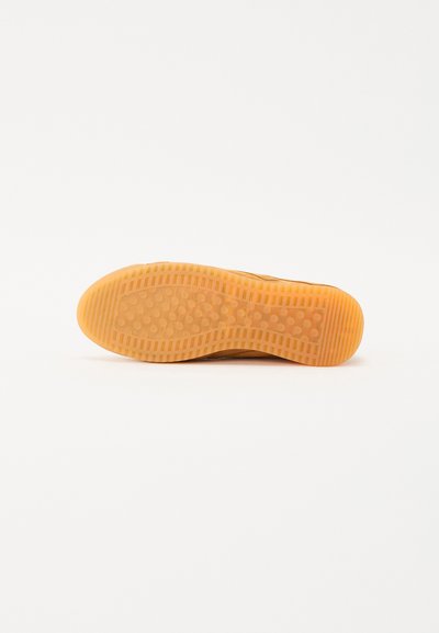 Suela de zapato de goma marrón con patrón de agarre texturizado. Punta redondeada y talón curvado. Acabado suave con ranuras circulares y horizontales.
