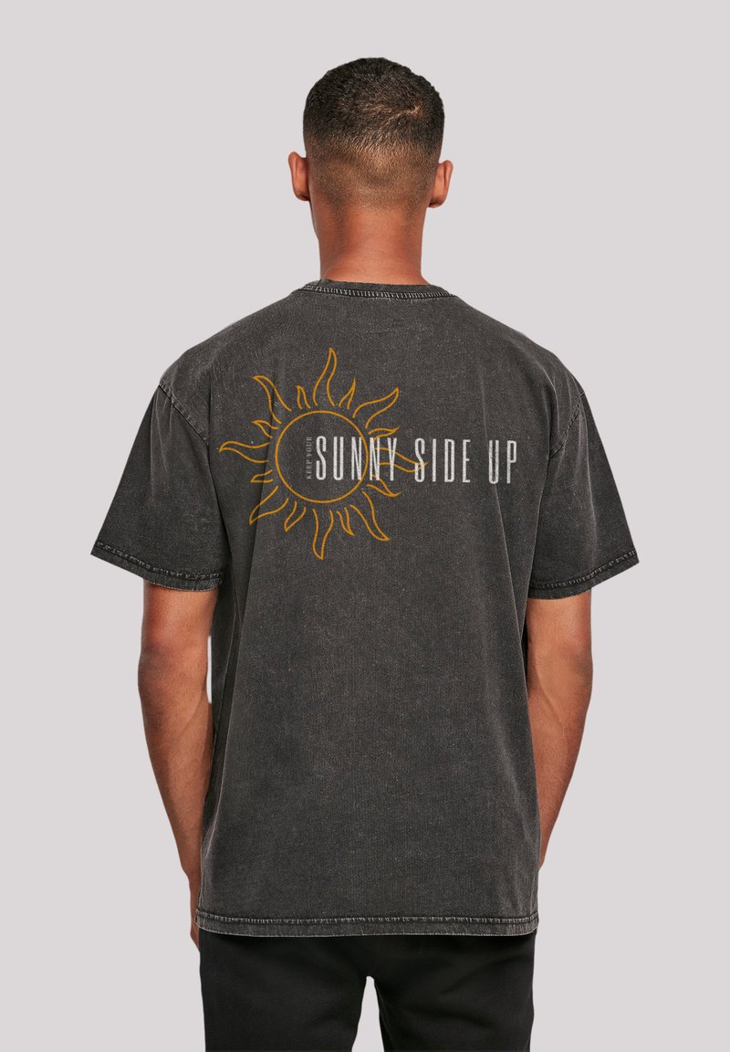 Charcoal gray cotton t-shirt featuring a sun graphic and "SUNNY SIDE UP" text in yellow and white. Short sleeves, relaxed fit.
