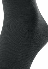 Calzino nero con texture a coste, vestibilità aderente e tallone rinforzato. Tessuto liscio con cuciture minime per il massimo comfort. Design e colore classico.