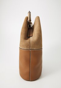 Brown bag with a textured brown canvas upper and smooth leather lower section. Features a top handle and contrasting white stitching.