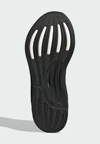 Suola di sneaker nera con un motivo testurizzato, scanalature pronunciate e accenti bianchi. Forma arrotondata con design flessibile e supporto dell'arco visibile.