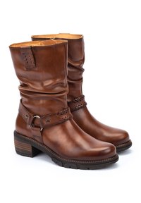 Bottines en cuir marron avec un design ample, un accent de sangle tissée et un talon épais solide. Le matériau texturé ajoute un intérêt visuel.