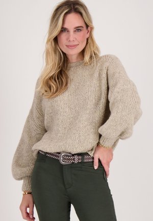 Lichtbeige oversized trui met een textuurgaren, ballonmouwen, gecombineerd met donkergroene broek en een gespikkelde riem. Eenvoudig, casual ontwerp.