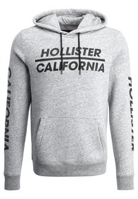 Felpa con cappuccio grigia con scritta nera "Hollister California". Presenta un cappuccio con coulisse, una tasca frontale e polsini e orlo a costine. Scritta su entrambe le maniche.