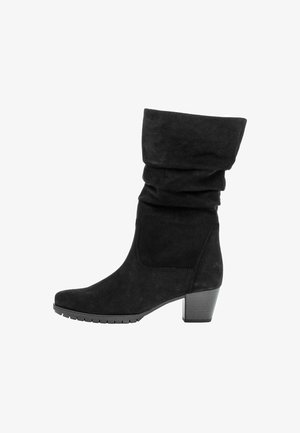 Zwarte suède enkellaars met een slouchy bovenkant, ronde neus en een chunky hak. Textuur oppervlak met een rubberen zool voor grip.