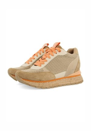 Baskets de sport beiges avec des matériaux en maille et en daim, lacets orange et semelle texturée et contrastée. Présente un design flexible et rembourré.