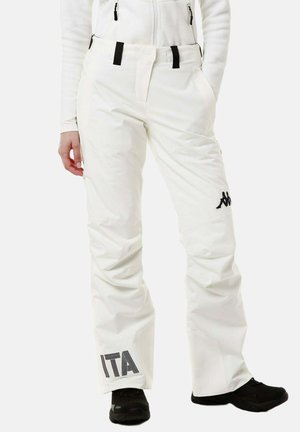 Pantaloni da sci bianchi con logo nero sulla coscia e scritta "ITA" sulla parte inferiore della gamba, indossati con scarpe nere, mano in tasca su sfondo semplice.