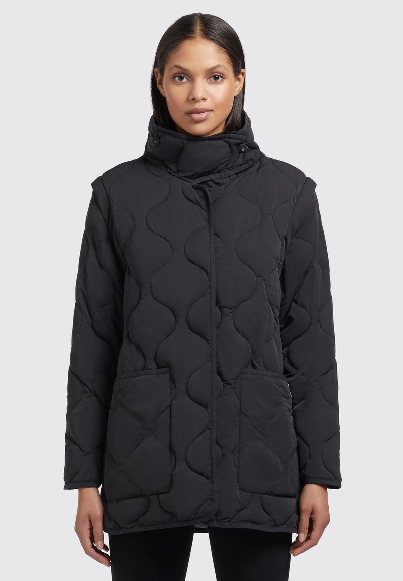 Doudoune noire matelassée avec un col haut, fermeture à pression et deux poches avant ; présente un motif de couture ondulé pour la texture.