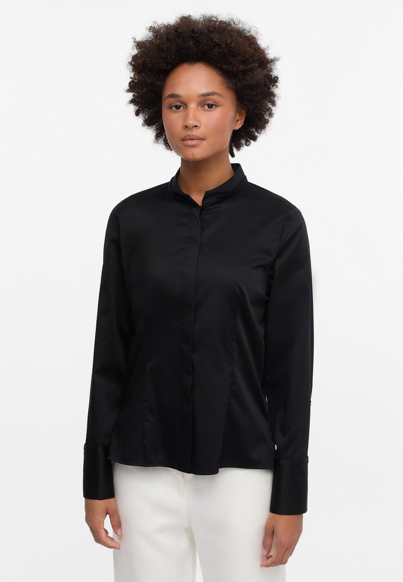Black satin long-sleeve shirt with a stand-up collar, featuring a button-down front and single cuffs, shown with light-colored pants.