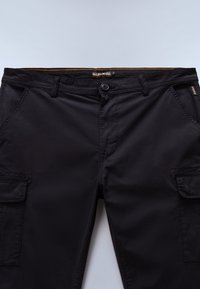 Czarne spodnie cargo z przednimi kieszeniami, szlufkami na pasek, zapięciem na guziki oraz pomarańczowym przeszyciem na wewnętrznej stronie pasa.