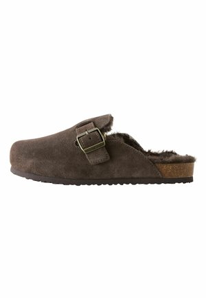 Hnedý semišový slip-on štucánek s nastaviteľnou kovovou prackou a mäkkou kožušinovou podšívkou, s plochou korkovou podrážkou.