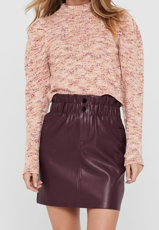 Pull en tricot dans des tons doux de rose et de crème avec un col haut, associé à une jupe moulante en simili cuir bordeaux dotée d'une taille élastique et de deux boutons.