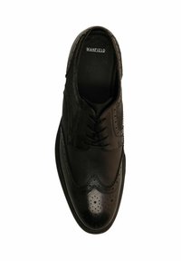 Zwarte brogueschoenen van een mix van glad leer en gestructureerde stof. Opvallende perforaties en vleugelpunten verbeteren het ontwerp.