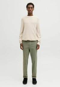 Cream textured sweater with long sleeves, paired with light green slim-fit trousers and black lace-up shoes. Simple, modern casual outfit.