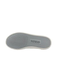 Suela de zapato de goma gris con una superficie texturizada, que presenta numerosos pequeños perforaciones y el logo "Geox" en el centro.