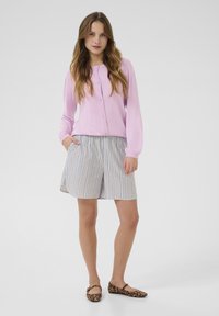 Light pink button-up cardigan with long sleeves, paired with striped shorts in blue and white. Brown leopard print flat shoes.