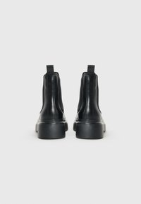 Black leather ankle boots with elastic side panels, a pull tab, and chunky rubber soles. Smooth texture and sleek design.
