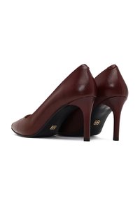 Escarpins en cuir bordeaux à bouts pointus et talons aiguilles fins ; ils présentent une finition brillante et un détail en logo doré sur le talon.