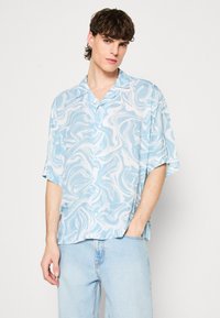 Camicetta a maniche corte realizzata in tessuto leggero, con un motivo marmorizzato blu e bianco, design con bottoni e vestibilità rilassata.