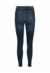 Jeans skinny blu scuro in denim, con vita media, cinque tasche e una leggera sfumatura lungo la coscia e l'orlo.