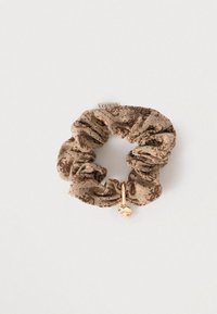 Καφέ scrunchie με σχέδιο από ύφασμα, με ένα χρυσό κρεμαστό διακοσμητικό σε σχήμα καρδιάς που έχει τρεις διαφανείς πέτρες.