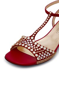 Rote Satin-Sandalen mit weit geöffnetem Zeh, verziert mit klaren und goldenen geometrischen Nieten, ausgestattet mit dünnen Knöchelriemen und einem glatten Innenfutter.