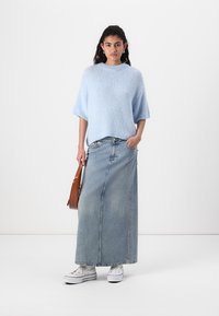 Svetlo modri pleteni pulover s kratkimi rokavi, v kombinaciji z dolgo denim krilo. Bele superge in rjava torba čez ramo dopolnjujeta obleko.