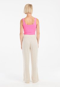 Strakke roze geribbelde tanktop gecombineerd met crèmekleurige wijde broek met een gestructureerd ruitpatroon en een zachte tailleband.