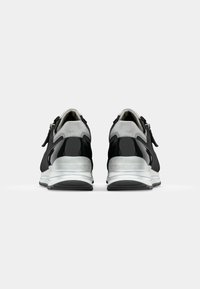 Black and gray sneakers with a textured upper, patent leather accents, reflective detailing, and a cushioned white midsole.